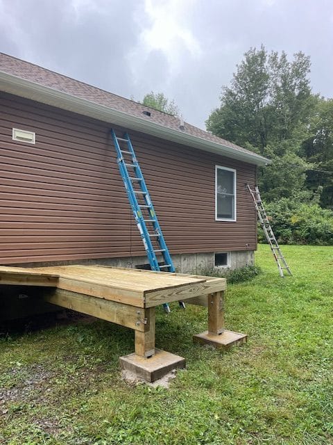 Commonwealth Maintenance crew installing seamless gutters on a residential property in Thompson, PA