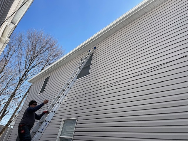 Commonwealth Maintenance crew installing seamless gutters on a residential home in Throop, PA